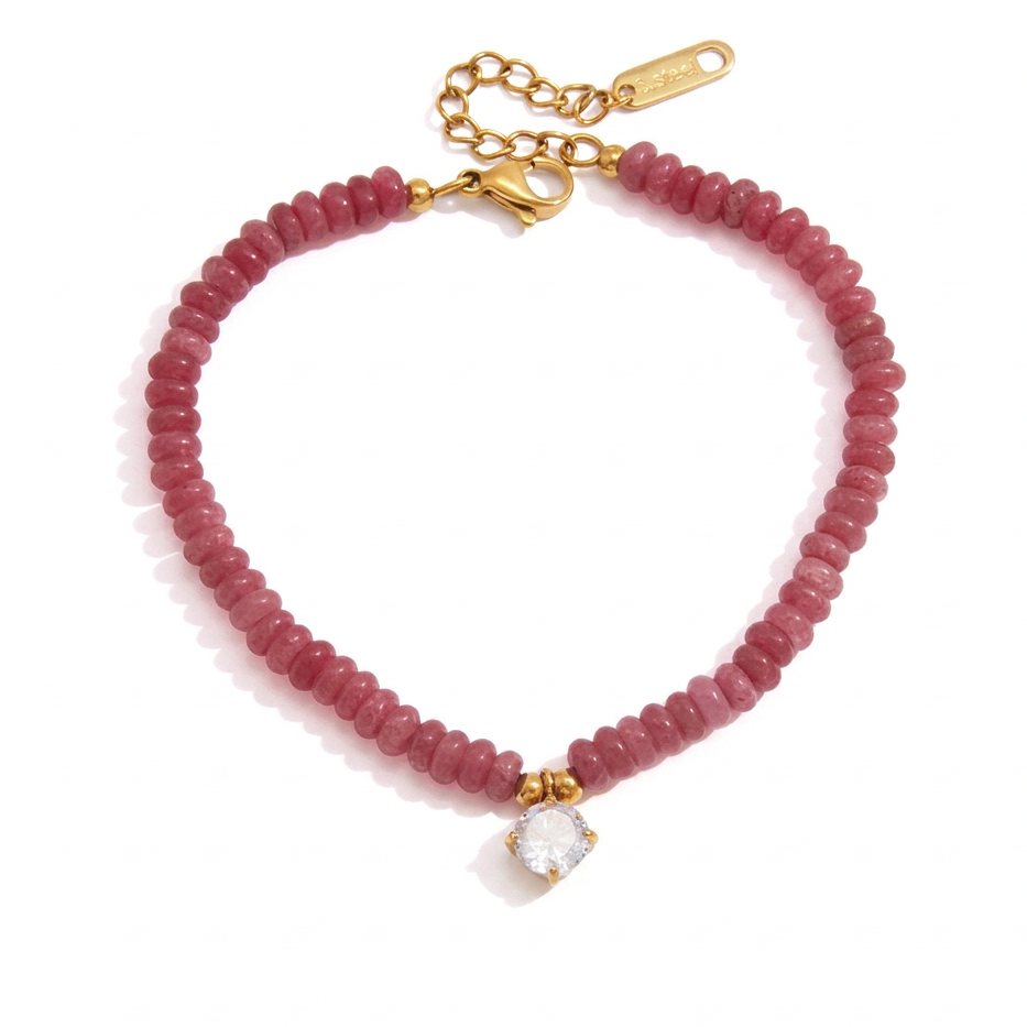 A pink beaded bracelet with a gold clasp and chain, featuring a small clear rhinestone charm. 